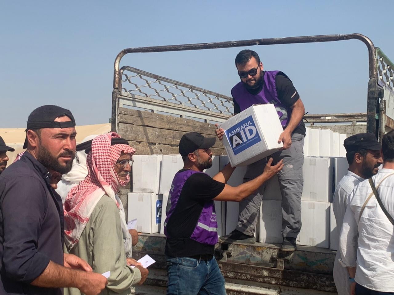 Ashraful Aid volunteers unloading relief parcels from a truck during a humanitarian distribution